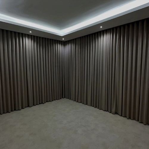 Corner view of an empty modern room with taupe-colored, floor-to-ceiling pleated blackout curtain Dubai installation
