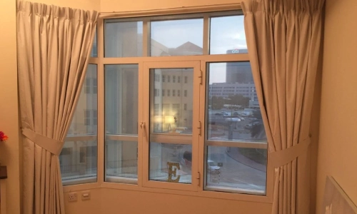 Interior view of a high-rise apartment showing tailored, pleated blackout curtains in Bluewaters