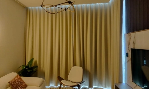Luxury living room interior featuring floor-to-ceiling beige blackout curtains in Bluewaters and a modern brass chandelier.
