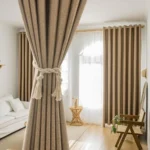 A bright, sunny living space featuring thermal blackout curtains in a textured, light brown_taupe color.
