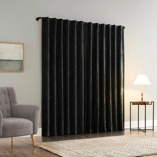 A pair of luxurious, floor-length velvet blackout curtains in black, hung on a dark rod against a light gray wall, creating a dramatic