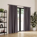 Dark grey Polyester blackout curtains covering glass French doors leading to a patio.