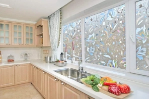 Modern kitchen featuring decorative kitchen window tinting with a colorful floral frosted pattern for privacy and style above a stainless steel sink.
