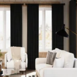A bright, modern living room featuring three panels of floor-to-ceiling chenille living room blackout curtains in charcoal black.