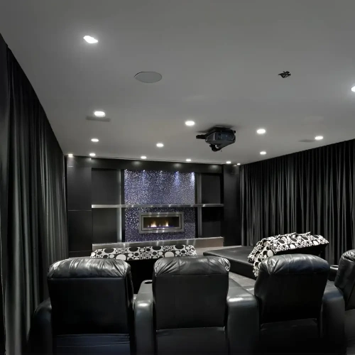A luxury home theater featuring floor-to-ceiling media room blackout curtains in sleek black fabric that line the walls.