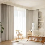 A serene, cream-colored interior featuring Pencil Pleat living room blackout curtains with tightly gathered folds