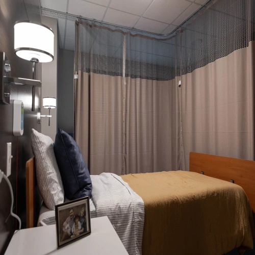 An empty bed in a hospital bedroom featuring blackout curtains that are drawn around the bed for privacy and light control.