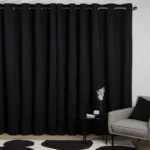 Charcoal-colored chenille living room blackout curtains hanging on a black rod in a contemporary interior.