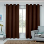 Eyelet living room blackout curtains in a neutral tone installed on multiple windows in a living room with beige furniture and soft ambient lighting.