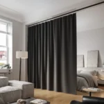 Innovative use of ceiling-mounted living room blackout curtains to separate a bedroom and living space.