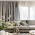 Modern interior design showcasing a neutral-toned sectional couch, a patterned rug, and pleated linen-look living room blackout curtains