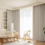 Pencil Pleat living room blackout curtains in a neutral off-white tone, elegantly framing large windows in a contemporary living room.