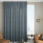 floor-length living room blackout curtains in charcoal grey installed in a contemporary lounge area with a grey sofa and dark wood furniture.