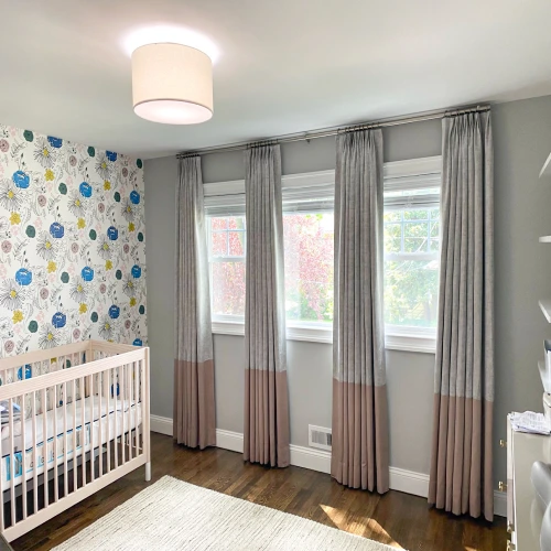 light gray wall with four floor-to-ceiling nurseries bedroom blackout curtains in a two-tone gray and dusty rose design.