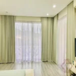 motorized living room blackout curtains in a soft sage green, paired with sheer white under-curtains for versatile light control and privacy.
