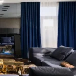 soft touch living room blackout curtains in navy blue installed in a high-ceilinged lounge with chevron wood flooring