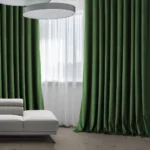 velvet living room blackout curtains in a rich forest green, elegantly draped and tied back to reveal a large window.