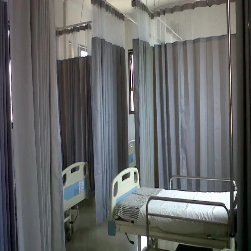 A clean and sterile medical ward featuring ceiling-tracked hospital blackout curtains in a practical light grey.