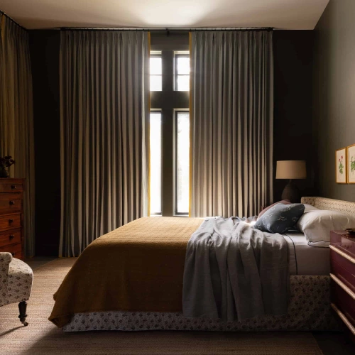 A cozy, dimly lit room featuring floor-to-ceiling bedroom blackout curtains in a muted grey with elegant yellow piping.