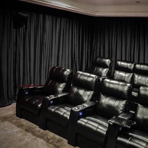 A luxury private cinema room featuring floor-to-ceiling home theater blackout curtains in a deep charcoal black.