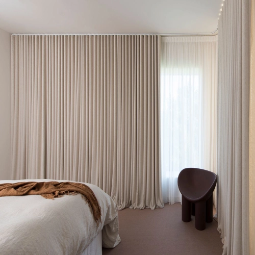 A minimalist bedroom showcasing floor-to-ceiling Wave Style Standard Blackout curtains in a soft beige linen-look fabric.