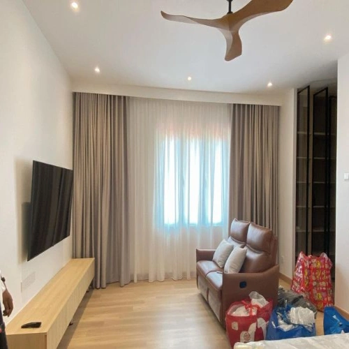 Contemporary living room featuring a layered window design with neutral blackout curtains in Dubai and central white sheers.