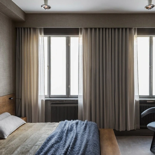 Modern bedroom with light grey blackout curtains in Dubai featuring a pencil pleat header.