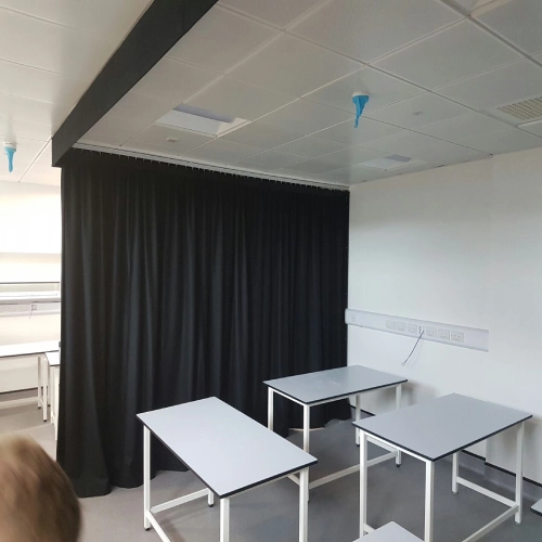 heavy-duty university blackout curtains in a solid black fabric, used as a room divider or light-control solution.