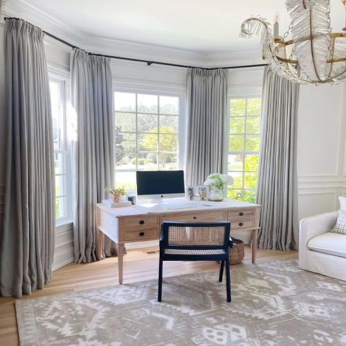 A bright, elegant home office featuring a bay window with a professional blackout curtains installation.