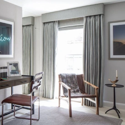 A bright, modern home office featuring floor-to-ceiling pinch pleat home office curtains in a textured grey fabric