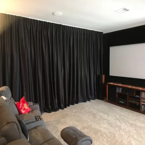 A dedicated home theater room featuring floor-to-ceiling media rooms blackout curtains in a sleek black satin finish.