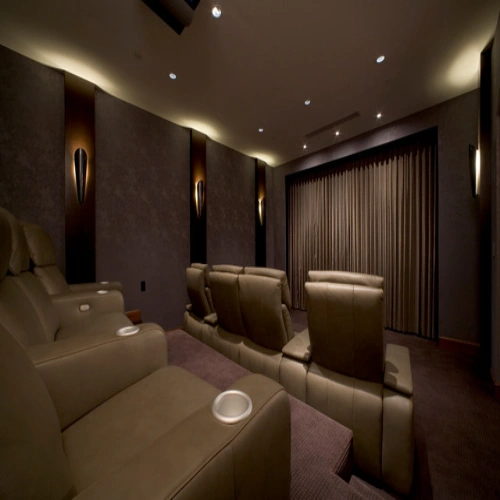 A luxury home cinema featuring tiered leather recliner seating and home theater blackout curtains in a neutral taupe fabric