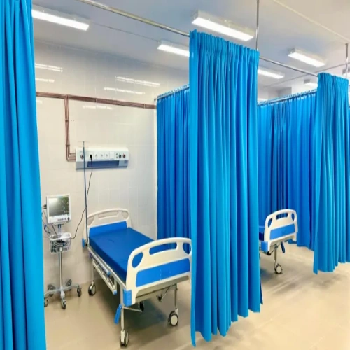 Patient beds separated by vibrant blue hospital blackout curtains hanging from ceiling tracks.