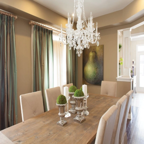 A sophisticated dining area featuring long, pleated dining area blackout curtains in a shimmering teal and bronze silk fabric, paired with sheer white panels.