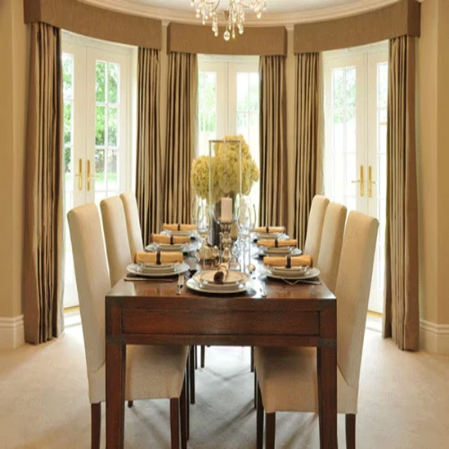 An elegant dining room set with a long wooden table and cream upholstered chairs, featuring heavy taupe dining area blackout curtains with matching fabric valances.