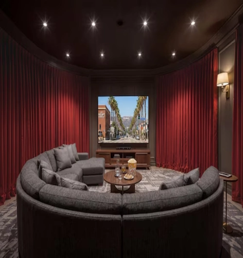 Red home theater blackout curtains along curved walls, surrounding a large screen, a grey sectional sofa
